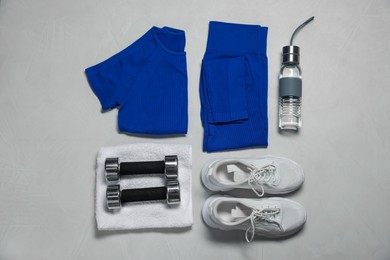 Photo of Sportswear, sneakers, dumbbells, towel and water bottle on gray textured background, flat lay