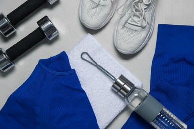 Photo of Sportswear, sneakers, dumbbells, towel and water bottle on gray textured background, flat lay