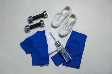 Photo of Sportswear, sneakers, dumbbells, towel and water bottle on gray textured background, flat lay