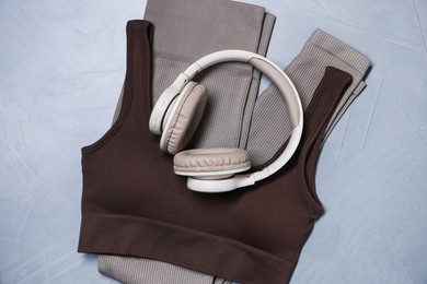 Photo of Sportswear and headphones on gray textured background, top view