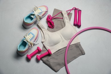 Photo of Sportswear, sneakers, hula hoop, skipping rope and dumbbells on gray textured background, flat lay