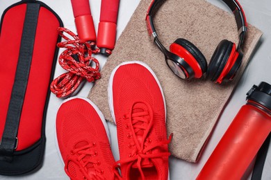 Photo of Sneakers, skipping rope, headphones and other accessories on gray background, flat lay