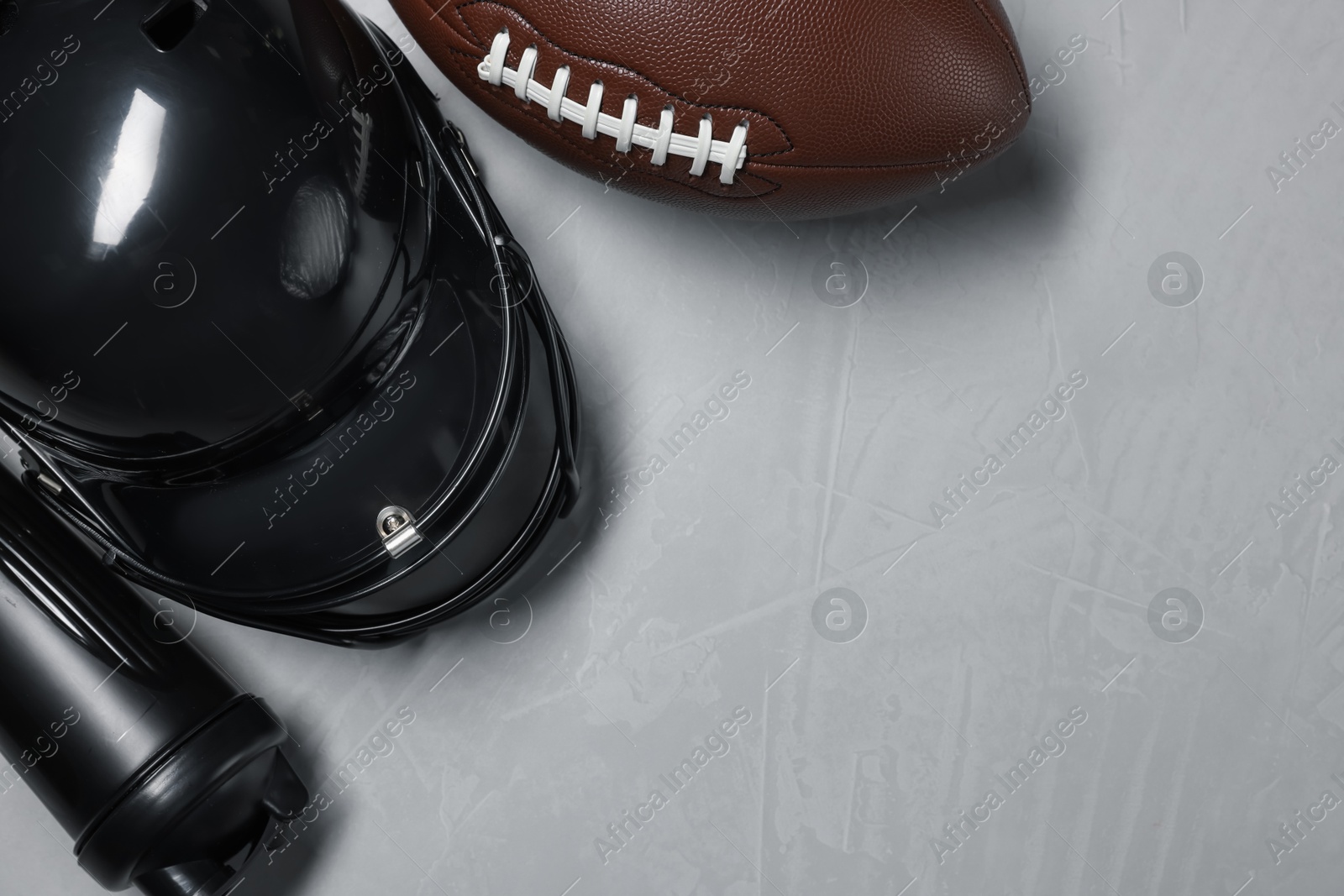 Protective helmet, American football ball and water bottle on gray textured background, flat lay. Space for text Photo of Protective helmet, American football ball and water bottle on gray textured background, flat lay. Space for text