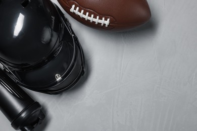 Photo of Protective helmet, American football ball and water bottle on gray textured background, flat lay. Space for text