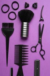 Photo of Different hairdresser's tools on violet background, flat lay
