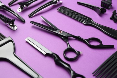 Photo of Different hairdresser's tools on violet background, closeup