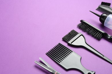 Photo of Different hairdresser's tools on violet background, closeup. Space for text