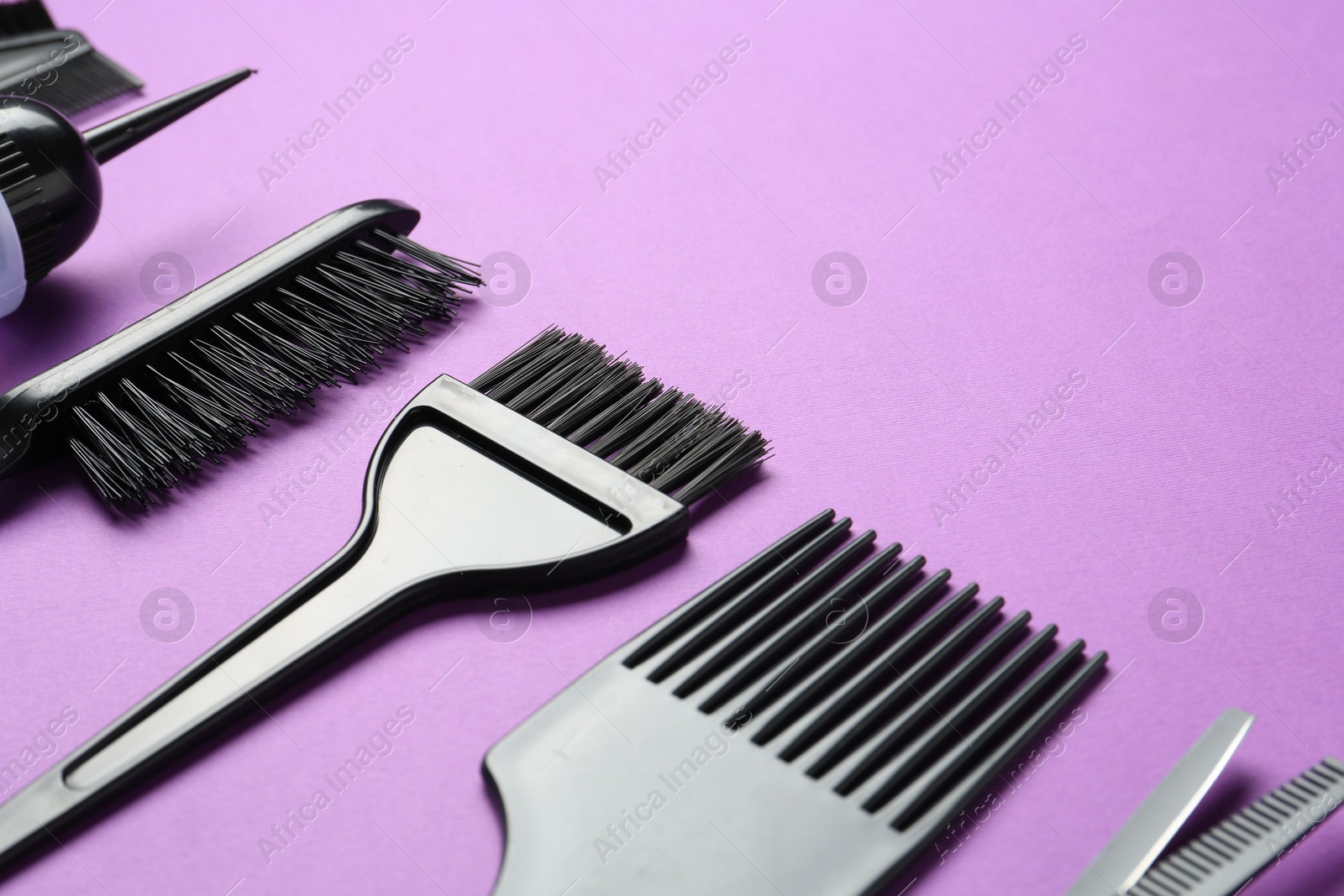 Photo of Different hairdresser's tools on violet background, closeup. Space for text