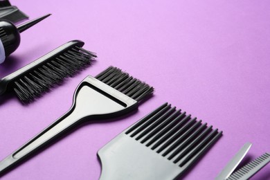 Photo of Different hairdresser's tools on violet background, closeup. Space for text