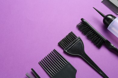 Photo of Different hairdresser's tools on violet background, flat lay. Space for text