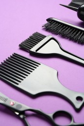 Photo of Different hairdresser's tools on violet background, closeup