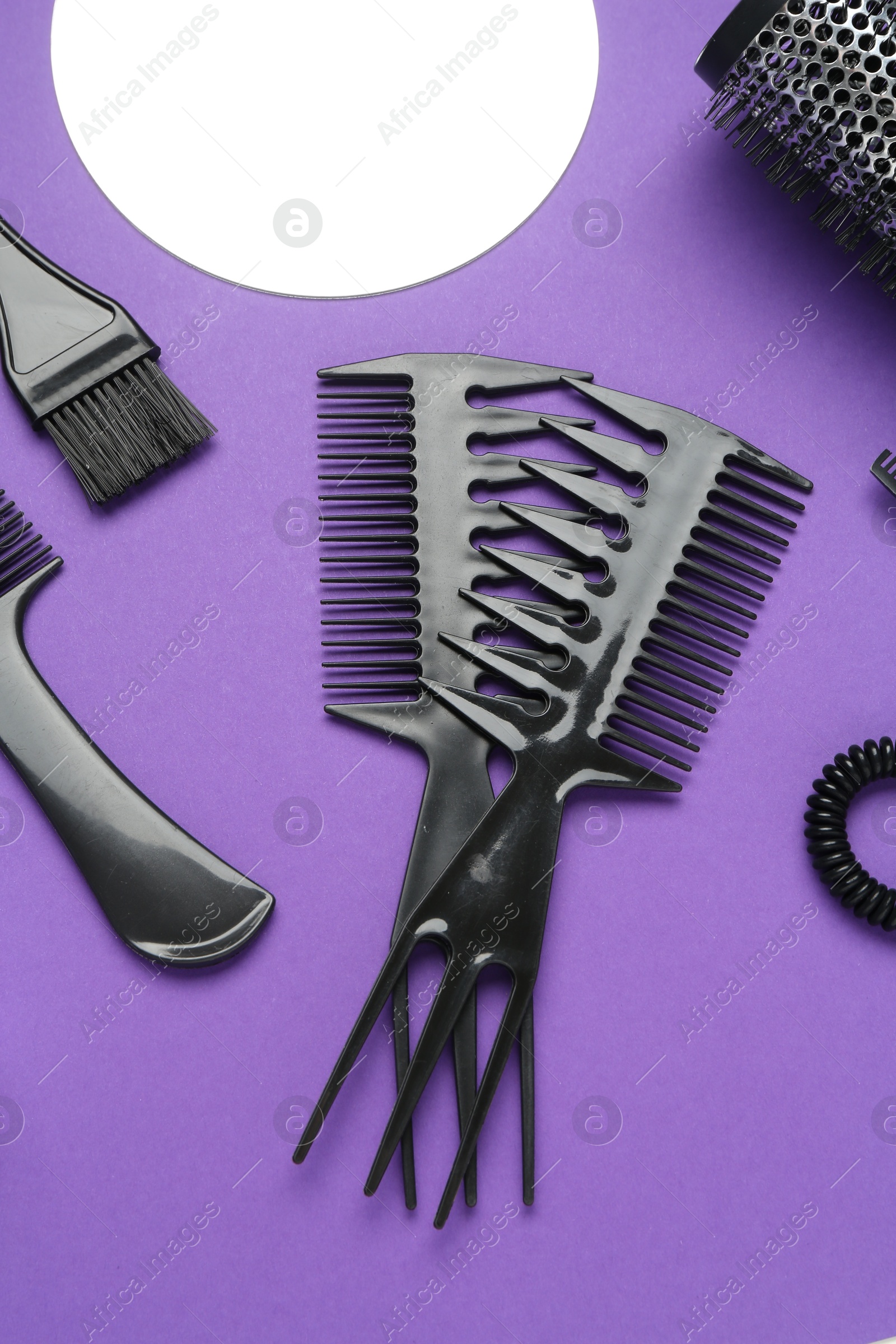 Photo of Different hairdresser's tools on purple background, flat lay