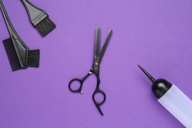Photo of Different hairdresser's tools on purple background, flat lay