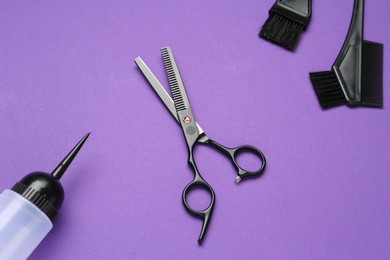 Photo of Different hairdresser's tools on purple background, flat lay