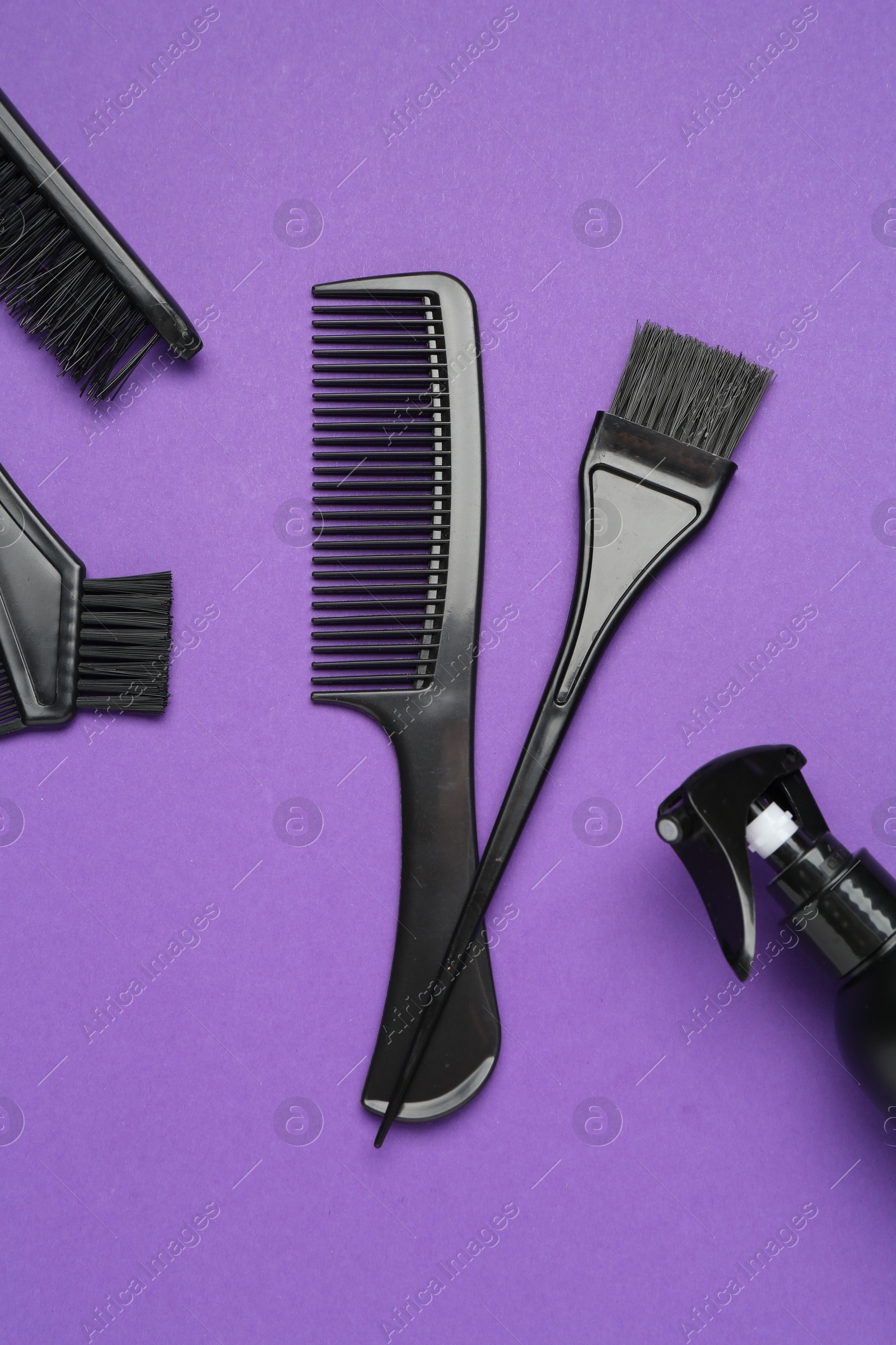 Photo of Different hairdresser's tools on purple background, flat lay