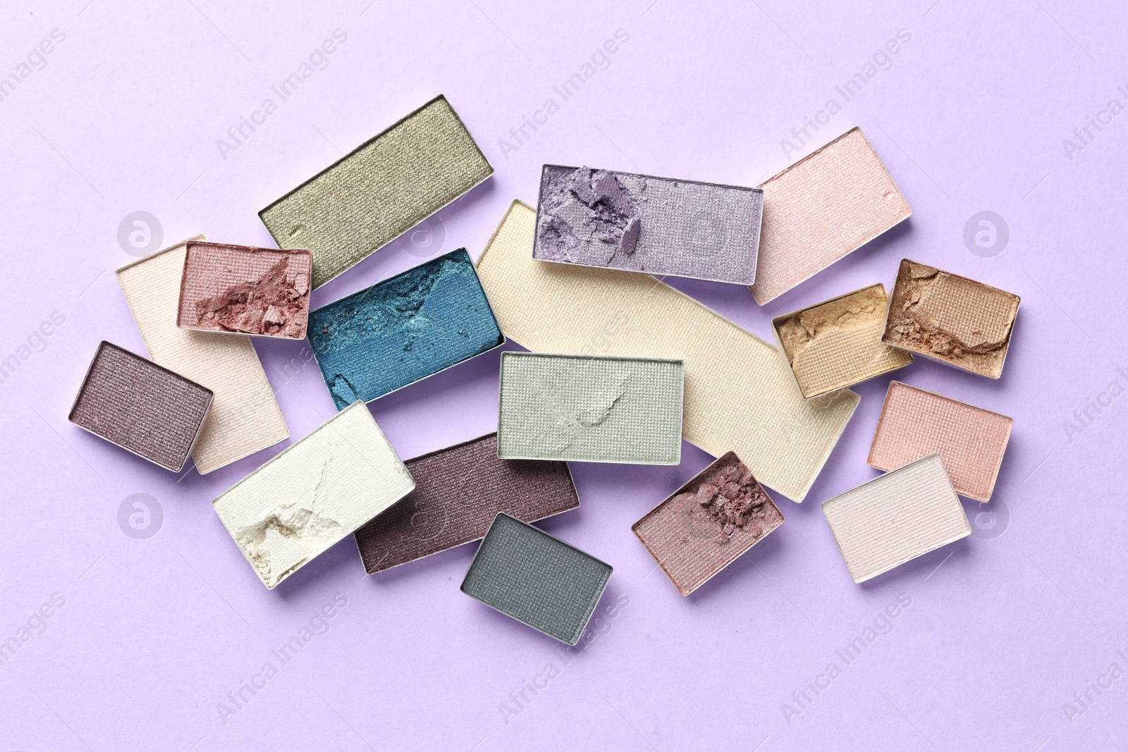 Beautiful eyeshadow refill pans on lilac background, flat lay Photo of Beautiful eyeshadow refill pans on lilac background, flat lay