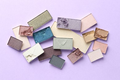 Photo of Beautiful eyeshadow refill pans on lilac background, flat lay