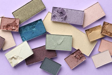 Photo of Beautiful eyeshadow refill pans on lilac background, flat lay