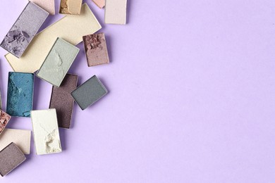 Photo of Beautiful eyeshadow refill pans on lilac background, flat lay. Space for text