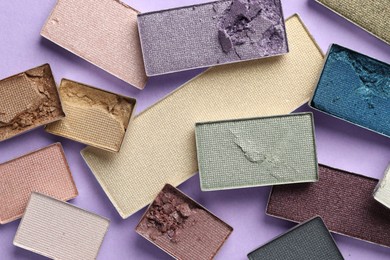 Photo of Beautiful eyeshadow refill pans on lilac background, flat lay