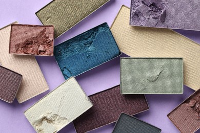 Photo of Beautiful eyeshadow refill pans on lilac background, flat lay