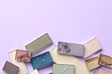Photo of Beautiful eyeshadow refill pans on lilac background, flat lay. Space for text