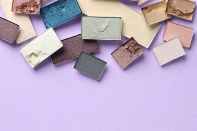 Photo of Beautiful eyeshadow refill pans on lilac background, flat lay. Space for text