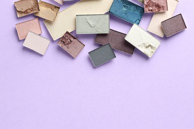 Photo of Beautiful eyeshadow refill pans on lilac background, flat lay. Space for text