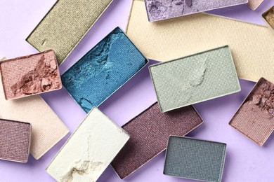 Photo of Beautiful eyeshadow refill pans on lilac background, flat lay