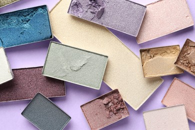 Photo of Beautiful eyeshadow refill pans on lilac background, flat lay