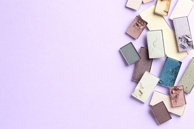 Photo of Beautiful eyeshadow refill pans on lilac background, flat lay. Space for text