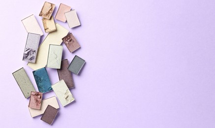 Photo of Beautiful eyeshadow refill pans on lilac background, flat lay. Space for text