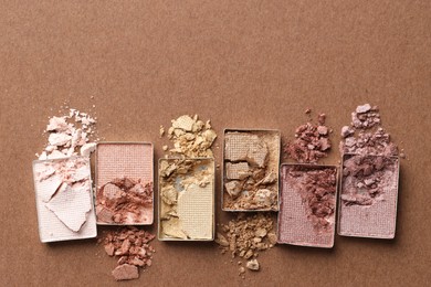Photo of Beautiful eyeshadow refill pans on brown background, flat lay. Space for text