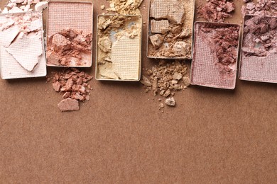 Photo of Beautiful eyeshadow refill pans on brown background, flat lay. Space for text