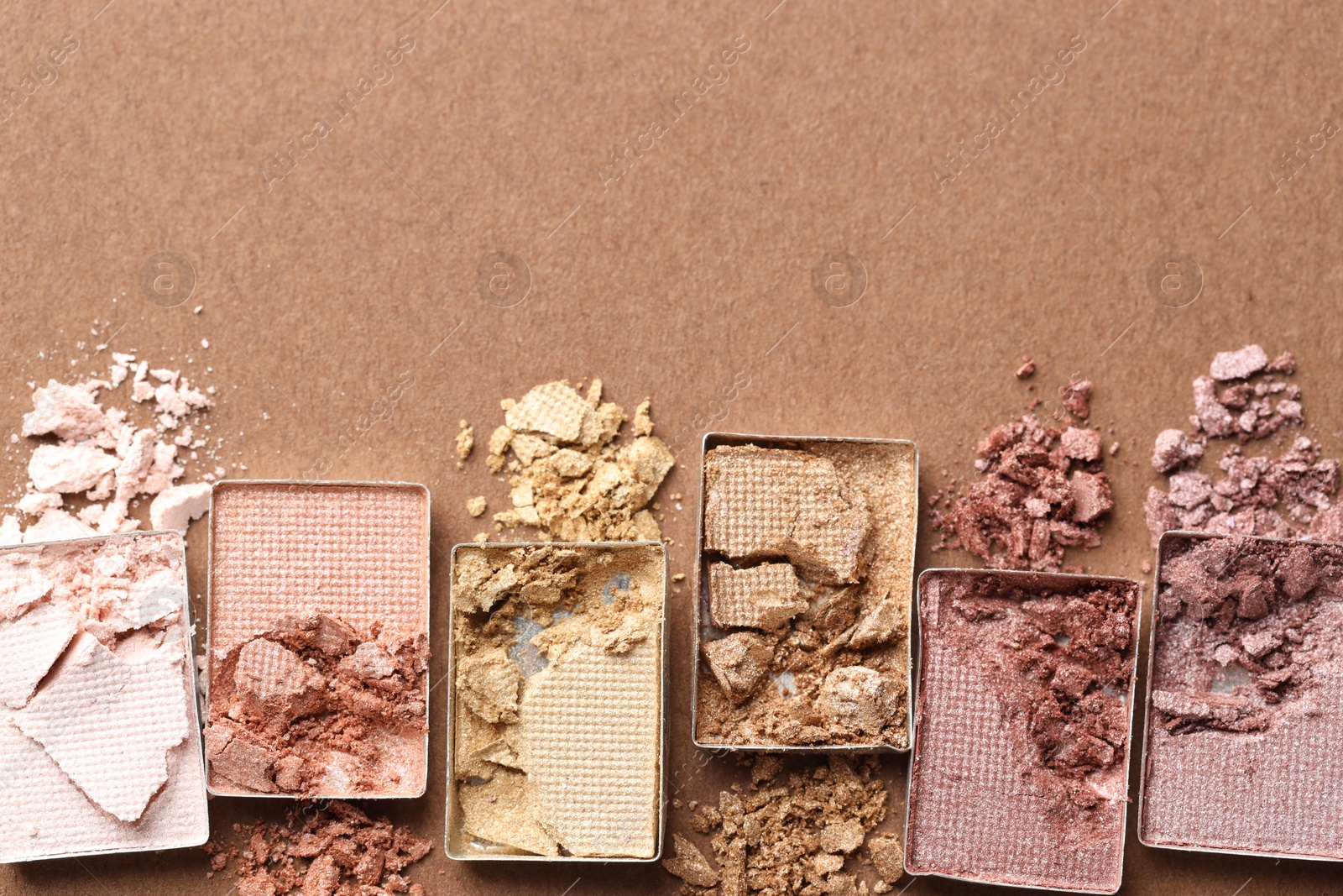 Beautiful eyeshadow refill pans on brown background, flat lay. Space for text Photo of Beautiful eyeshadow refill pans on brown background, flat lay. Space for text