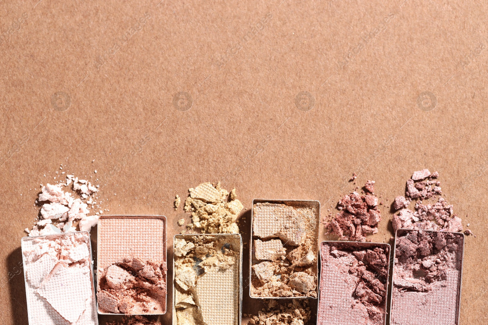 Beautiful eyeshadow refill pans on brown background, flat lay. Space for text Photo of Beautiful eyeshadow refill pans on brown background, flat lay. Space for text