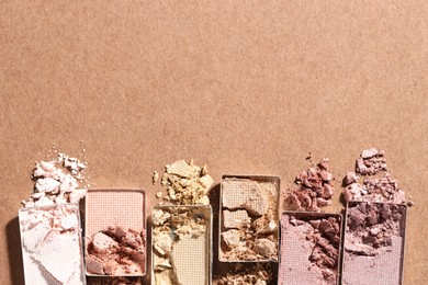Photo of Beautiful eyeshadow refill pans on brown background, flat lay. Space for text