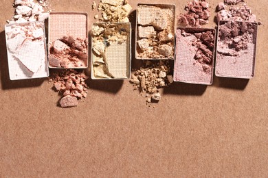 Photo of Beautiful eyeshadow refill pans on brown background, flat lay. Space for text