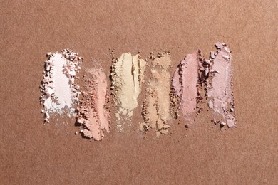 Photo of Different eyeshadows smudges on brown background, flat lay