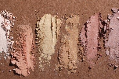 Photo of Different eyeshadows smudges on brown background, flat lay