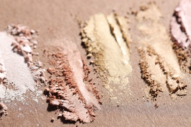 Photo of Different eyeshadows smudges on brown background, closeup