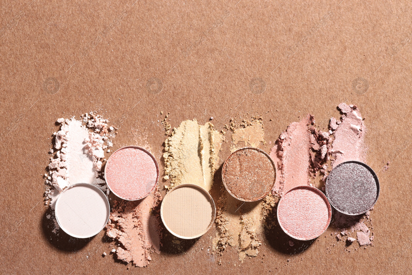 Beautiful eyeshadow refill pans on brown background, flat lay. Space for text Photo of Beautiful eyeshadow refill pans on brown background, flat lay. Space for text
