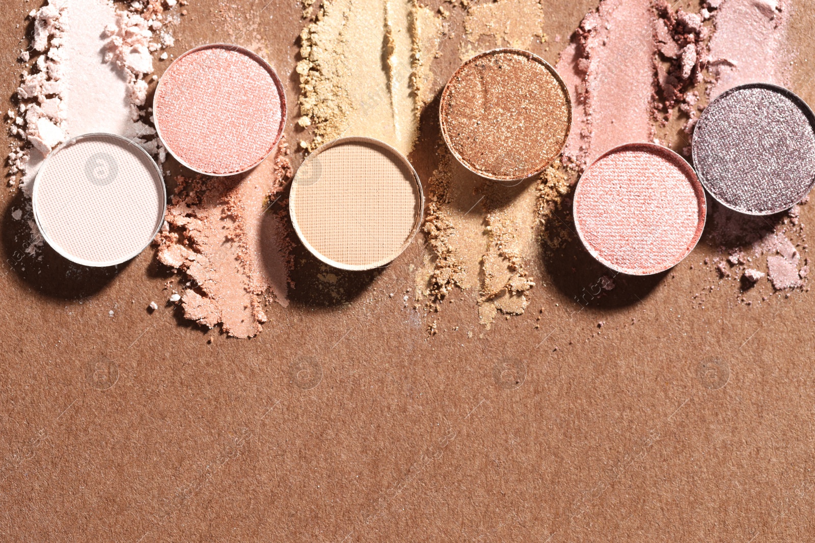 Beautiful eyeshadow refill pans on brown background, flat lay. Space for text Photo of Beautiful eyeshadow refill pans on brown background, flat lay. Space for text