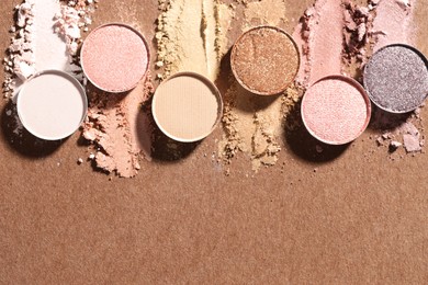 Photo of Beautiful eyeshadow refill pans on brown background, flat lay. Space for text