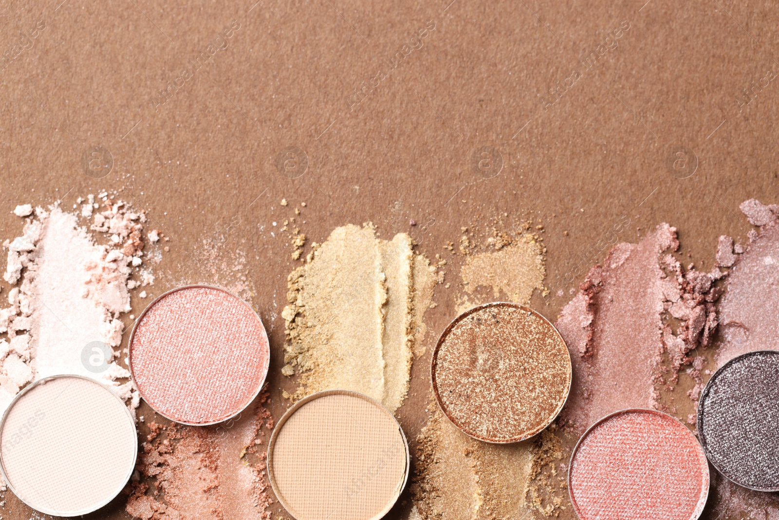 Beautiful eyeshadow refill pans on brown background, flat lay. Space for text Photo of Beautiful eyeshadow refill pans on brown background, flat lay. Space for text