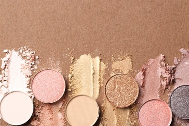 Photo of Beautiful eyeshadow refill pans on brown background, flat lay. Space for text