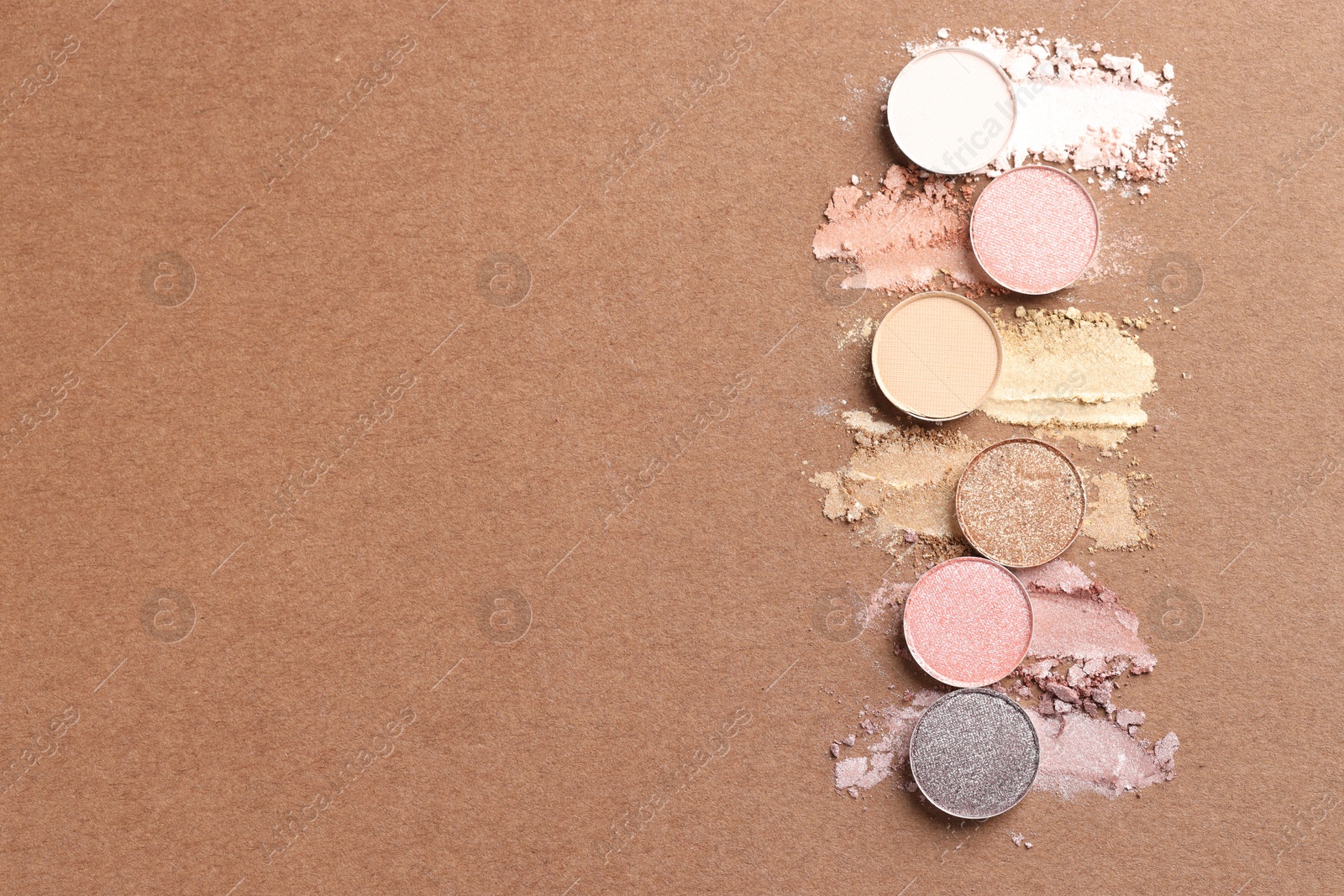 Beautiful eyeshadow refill pans on brown background, flat lay. Space for text Photo of Beautiful eyeshadow refill pans on brown background, flat lay. Space for text