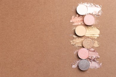 Photo of Beautiful eyeshadow refill pans on brown background, flat lay. Space for text