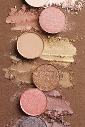 Photo of Beautiful eyeshadow refill pans on brown background, flat lay
