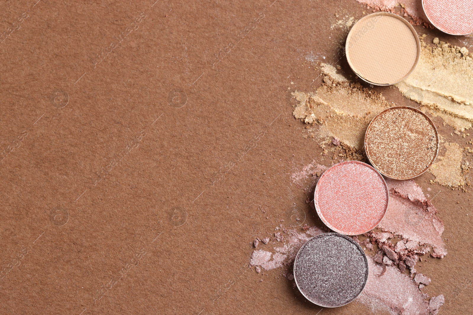 Beautiful eyeshadow refill pans on brown background, flat lay. Space for text Photo of Beautiful eyeshadow refill pans on brown background, flat lay. Space for text